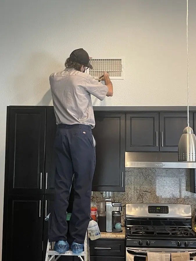 Technician inspecting an air vent during HVAC service in Darlington